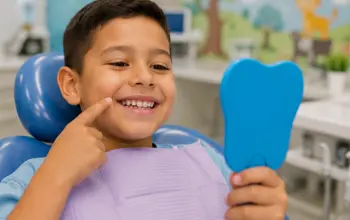 Smiling child holding a dental mirror during a comfortable pediatric dental visit.